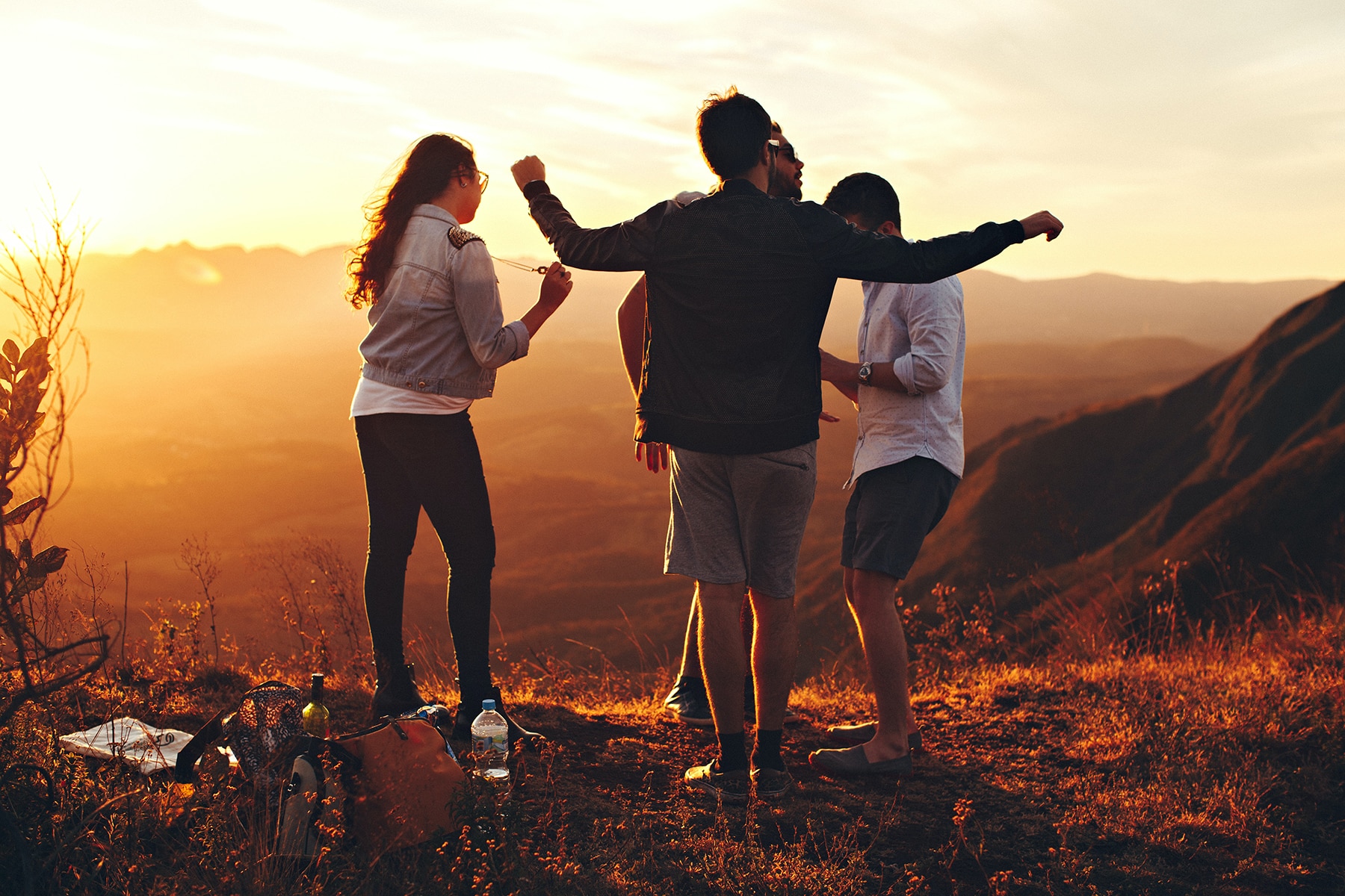 4 young adults on hilltop at sunset
