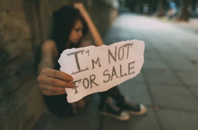 Teen girl holding sign "I'm NOT for sale."