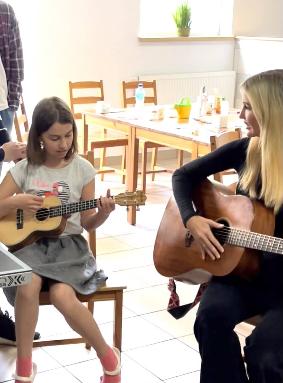 Ivanka Trump playing guitar with young girl.