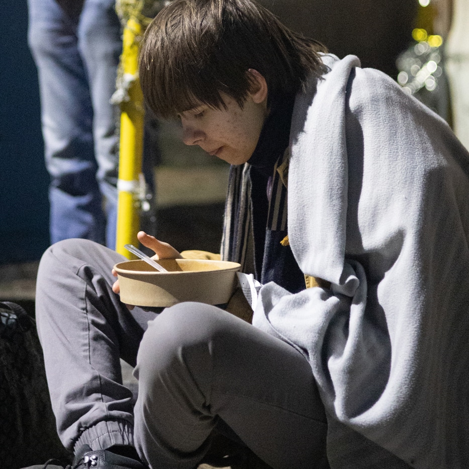 Boy eating soup while sitting on the floor in Ukraine.